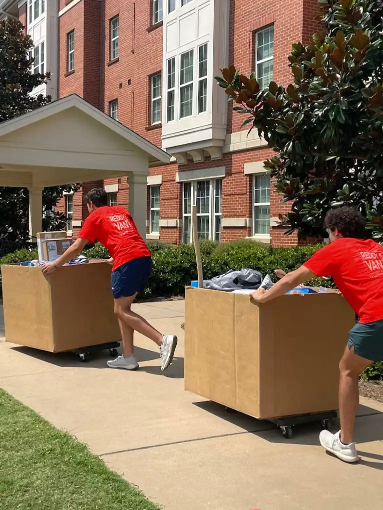 College student movers loading boxes and furniture during a campus move.